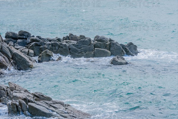 Ocean waves meeting a rugged coastline under overcast skies, in South Korea