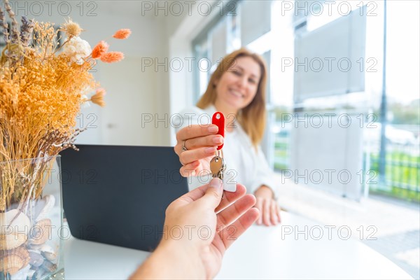 Unrecognizable client taking keys of a new home from real estate agent in the office