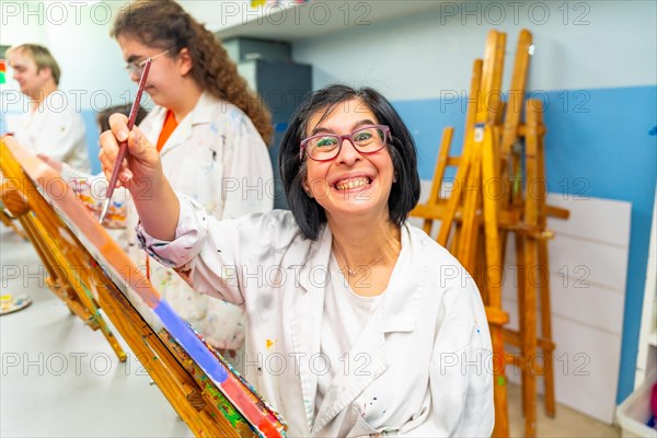 Portrait of an adult excited disabled woman smiling at camera during a painting class