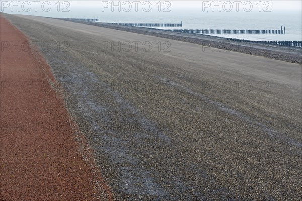 Wide view over a beach with breakwaters and a calm sea