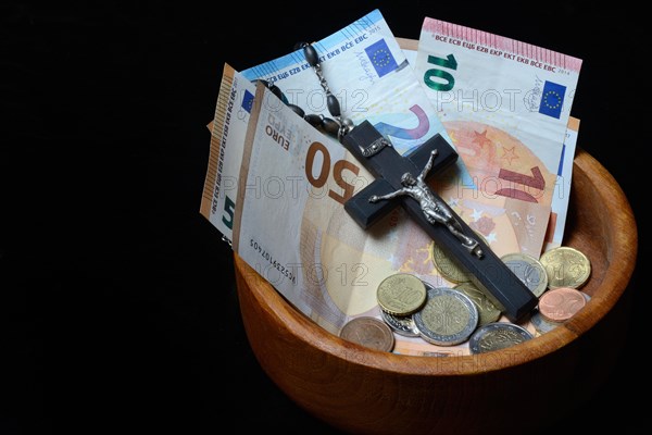 Crucifix and banknotes in a bowl, church and money, church tax