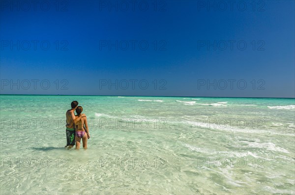 Couple standing in the turquoise water of the island of Nosy Iranja near Nosy Be, Madagascar, Africa