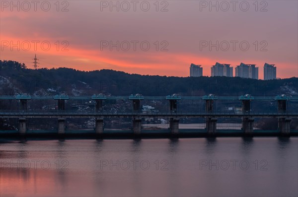 Serene twilight over a river with a dam and reflected cityscape, in South Korea