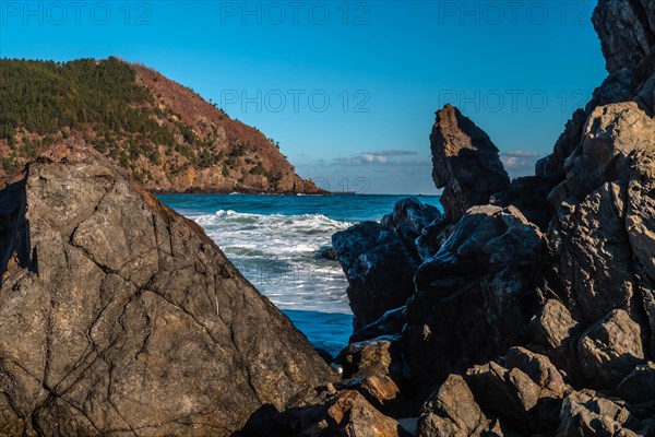 Magnificent cliff view with waves colliding against large rocks on a sunny day, in South Korea