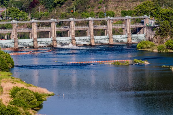 Landscape of dam releasing water through one floodgate into river with blue water located near Daejeon South Korea