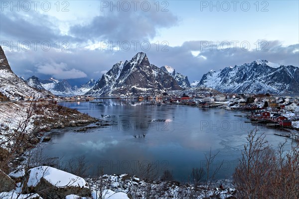 Twilight over a snowy village in Lofoten with calm waters and mountain backdrop, Lofoten