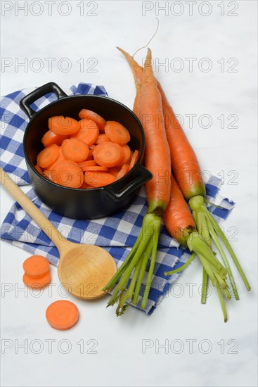 Carrot slices in pots and wooden spoon, carrot (Daucus carota)