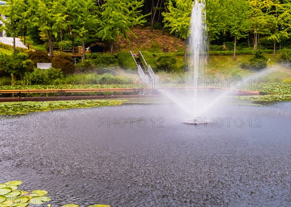 Water from a fountain cascades down creating a peaceful scene in a green park, in South Korea