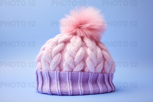 Pink and purple knitted winter hat with pompom on pastel blue background. KI generiert, generiert AI generated