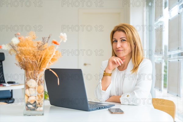 Horizontal photo with copy space of a female real estate agent smiling at camera sitting in the office in front of a computer