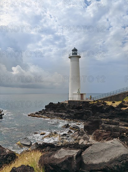 White lighthouse on a steep coast. Dramatic clouds with a view of the sea, pure Caribbean at Le Phare du Vieux-Fort, on Guadeloupe, French Antilles, France, Europe