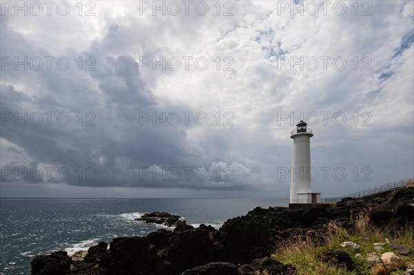 White lighthouse on a steep coast. Dramatic clouds with a view of the sea, pure Caribbean at Le Phare du Vieux-Fort, on Guadeloupe, French Antilles, France, Europe