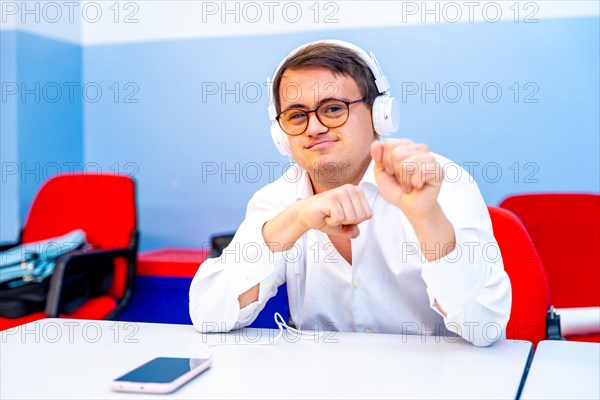Man with down syndrome listening to music with phones sitting indoors