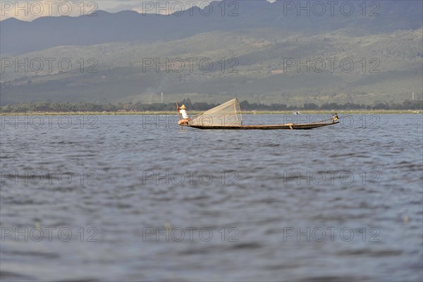Fisherman in a small boat in the middle of the water, mountains in the background, Inle Lake, Myanmar, Asia