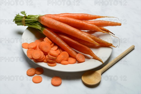 A bunch of carrots and carrot slices on a plate, Daucus carota