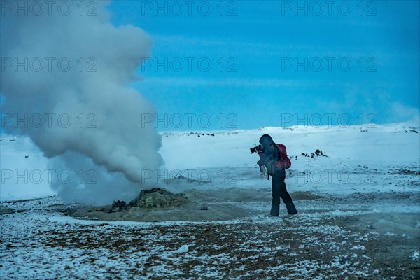 Adventurous photographer woman in winter in Iceland photographing in the Hverir or Namafjall Geothermal Area