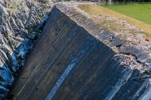 Water trickles down a concrete dam scattered with leaves, in South Korea