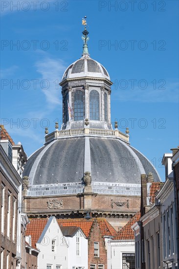 The dome of an old building rises into the blue sky above city buildings, Middelburg, Zeeland, Netherlands