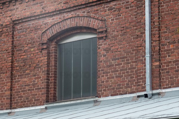 Arched window in a brick building with a traditional tiled roof