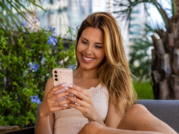 Close-up of a beautiful woman sitting on a sofa while writting a message on her smartphone