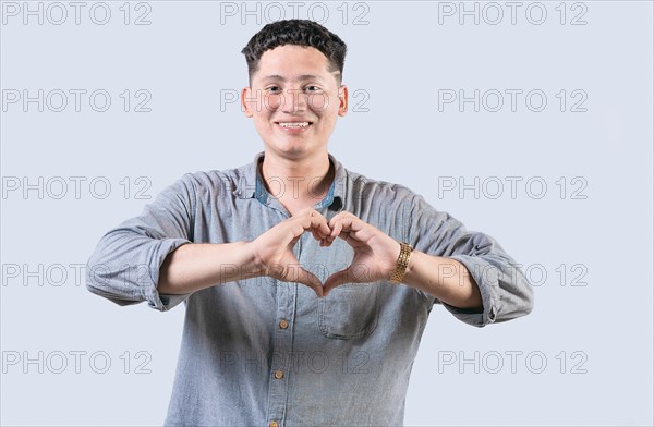 Handsome young man making heart shape with hands isolated. Happy guy making heart shape with hands