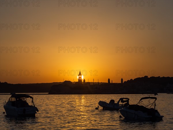 Boats anchoring in a bay, sunset, silhouette of the church towers of Rab, town of Rab, island of Rab, Kvarner Gulf Bay, Croatia, Europe