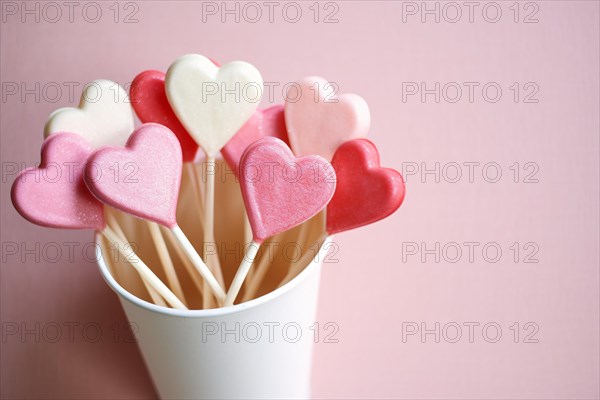 Paper cup with heart shaped pink, red and white popsicles. KI generiert, generiert AI generated