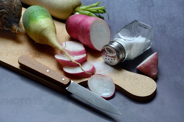 Various radishes on a wooden board, cut up and sliced