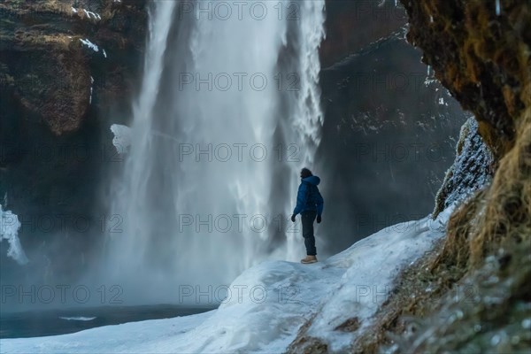 Silhouette of woman in winter in Iceland visiting Skogafoss waterfall