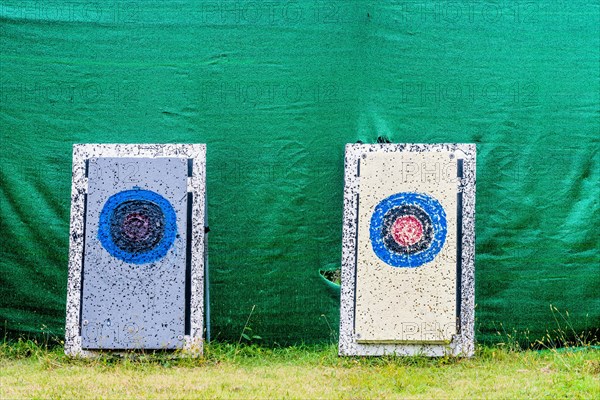 Two archery targets with mud splatters against a green backdrop on grass, in South Korea