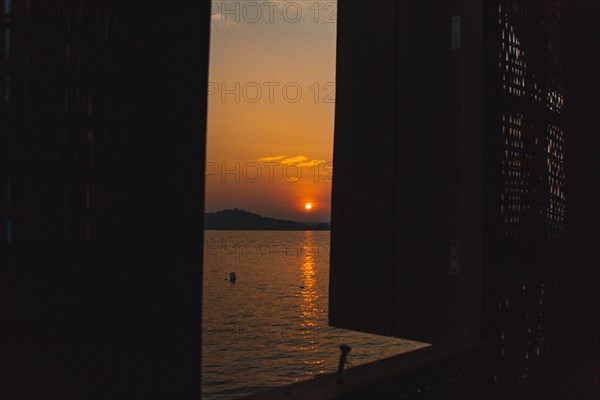View of the sunset over the sea from a wooden window in Koh Sdach Island in Cambodia