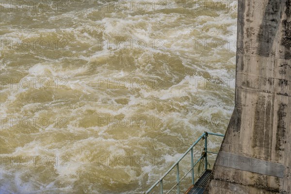 Churning turbulent waters rush by the base of a concrete bridge pillar, in South Korea