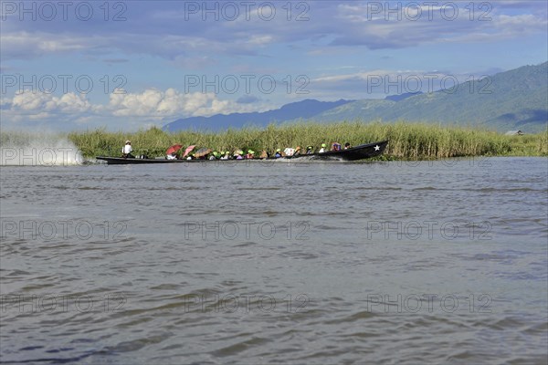 Group of people in a long boat on calm water, Inle Lake, Myanmar, Asia