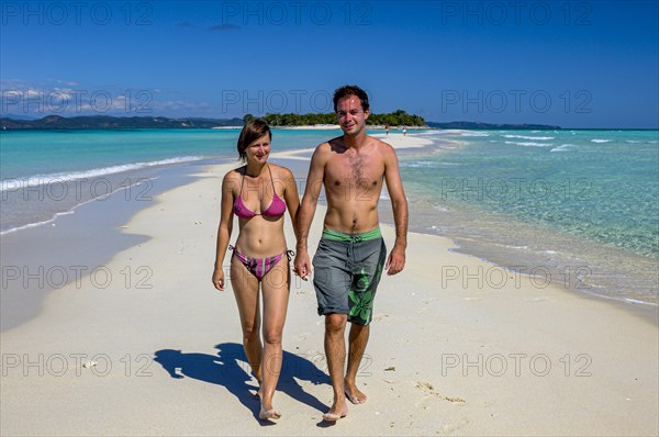 Couple walking on a white sand beach on the island of Nosy Iranja near Nosy Be, Madagascar, Africa
