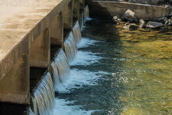 Water flowing smoothly over a concrete dam spillway, in South Korea