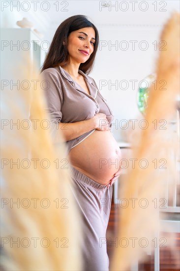 Vertical portrait of a beauty pregnant woman smiling at camera while touching her belly