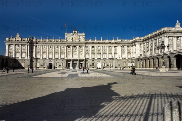 A majestic palace on a sunny day, people stroll around the spacious forecourt Madrid Spain