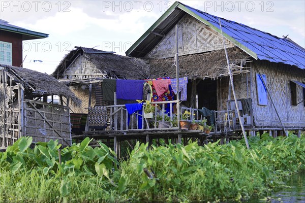 Traditional bamboo hut in a floating village with clothesline under a cloudy sky, Inle Lake, Myanmar, Asia