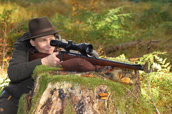 Huntress aims rifle with telescopic sight, Allgaeu, Bavaria, Germany, Europe