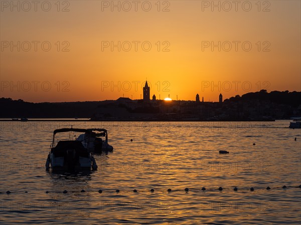 Sunset, silhouette of the church towers of Rab, boats anchoring in a bay, town of Rab, island of Rab, Kvarner Gulf Bay, Croatia, Europe