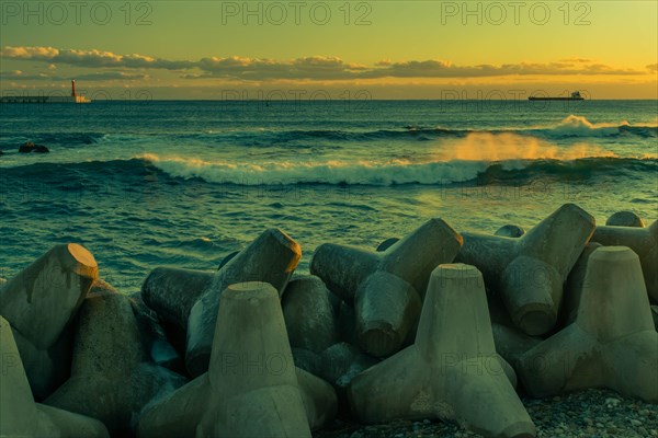 Vibrant sunset over ocean with silhouette of tetrapods on the breakwater, in South Korea