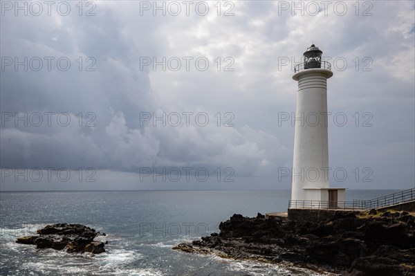 White lighthouse on a steep coast. Dramatic clouds with a view of the sea, pure Caribbean at Le Phare du Vieux-Fort, on Guadeloupe, French Antilles, France, Europe