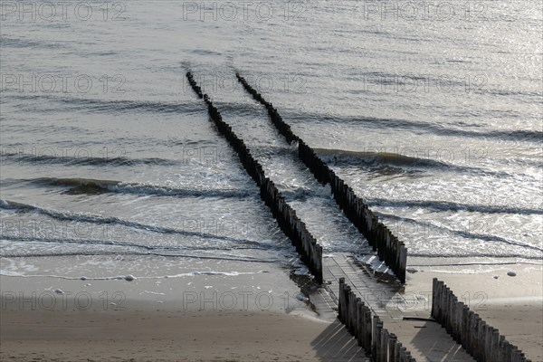 Old wooden groynes jut out into the sea, lapped by undulating water