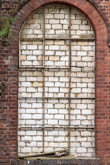 Arched window walled up with visible decay and texture