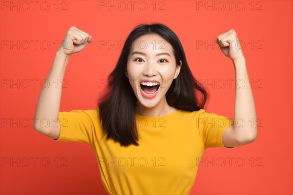 Happy successfull Asian woman cheering in front of orange background. KI generiert, generiert AI generated