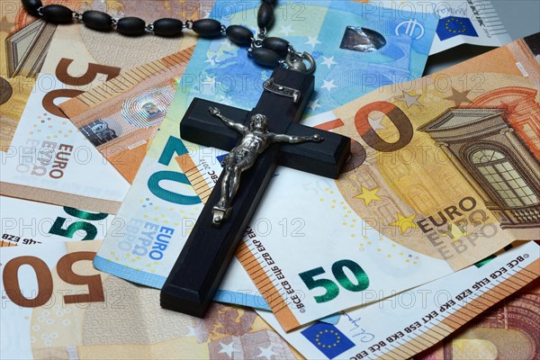 Crucifix and banknotes, church and money, church tax