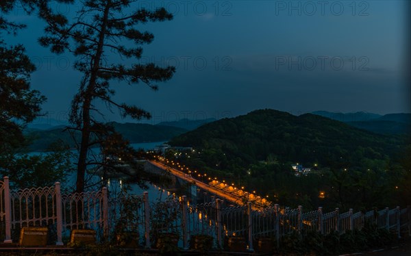 Blue hour view featuring an illuminated bridge and distant mountains, in South Korea