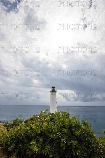 White lighthouse on a steep coast. Dramatic clouds with a view of the sea, pure Caribbean at Le Phare du Vieux-Fort, on Guadeloupe, French Antilles, France, Europe