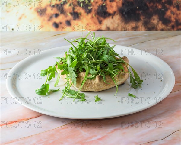 Fugazzeta Argentinian Stuffed Pizza is filled with a layer of mozzarella cheese with sliced onions and even more cheese on top closeup in the plate on the wooden table. Horizontal top view from above, pizza