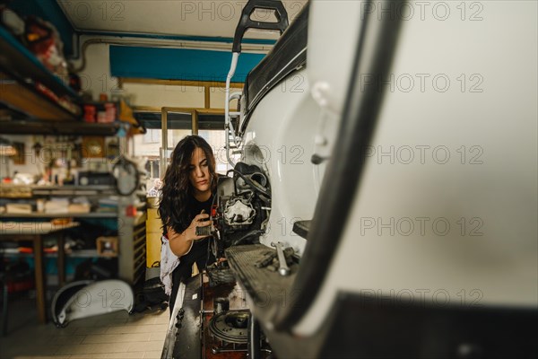 Female mechanic engaging in hands-on motorbike maintenance at a workshop station, latino woman in traditional masculine jobs concept, feminine power in real life
